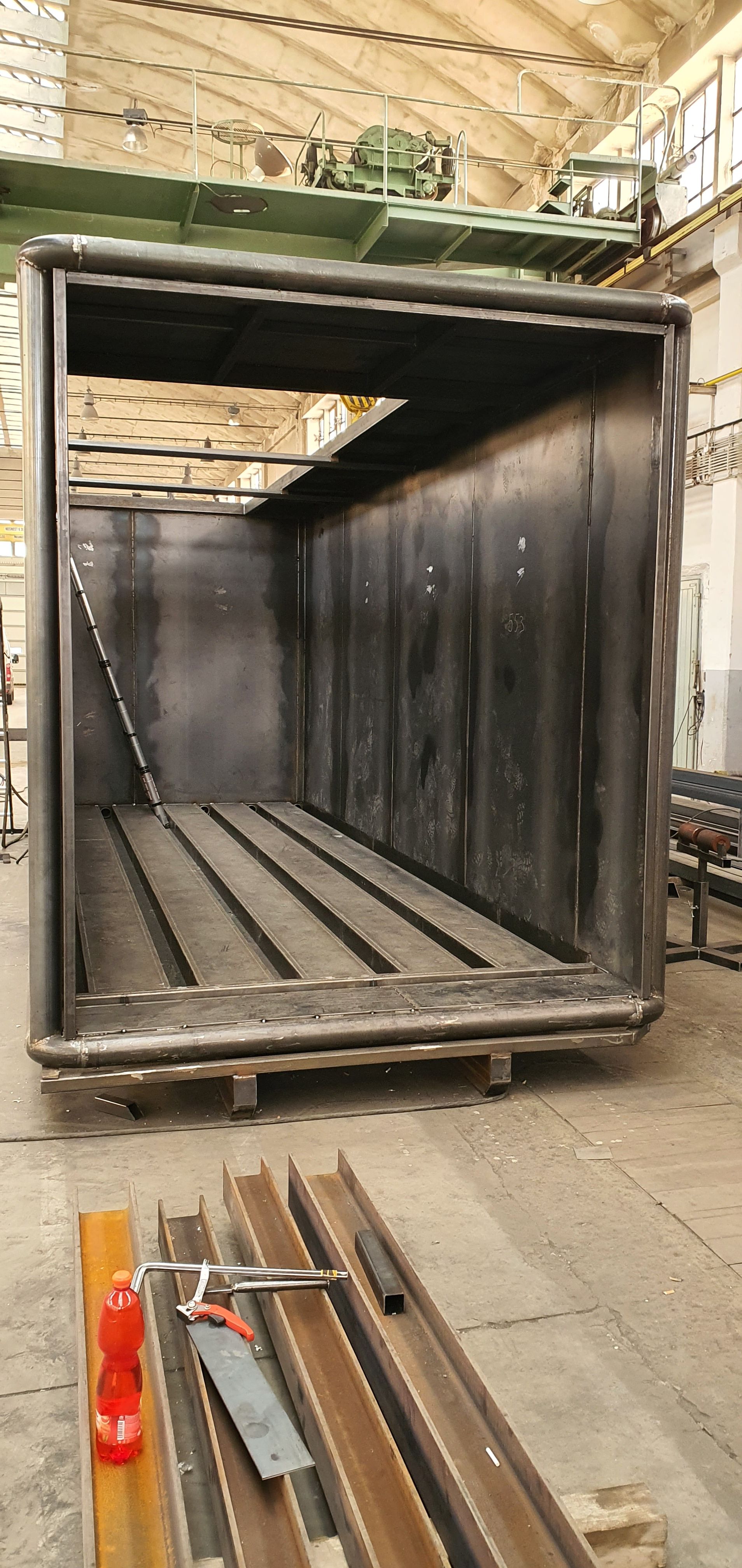 Detailní pohled do surového ocelového rámu vnitřní části biofermentoru během výroby. Jsou viditelné podlahové profily a stěny z ocelových plátů bez povrchové úpravy.